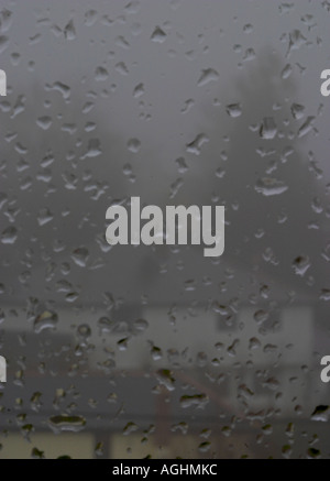 A foggy, rainy, winter's day looking out through a window with houses in background Stock Photo