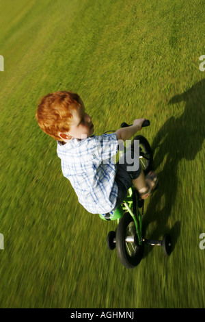 Boy cycling on a bike with stabilisers Stock Photo