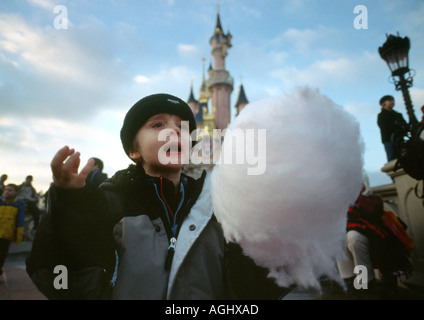 small boy in coat eating candy floss in winter at the park Stock Photo