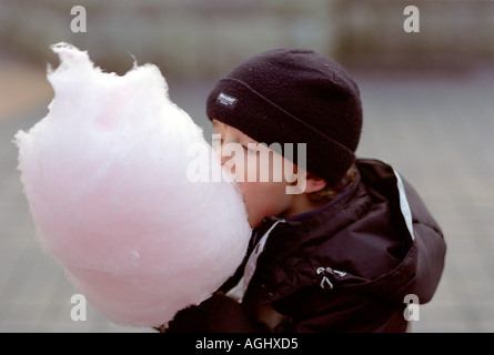 small boy in coat eating candyfloss in winter at the park Stock Photo