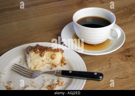 Half eaten coffee cake on plate with spilled cup of coffee Stock Photo