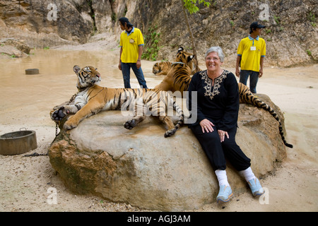 Woman posing with Tiger at Kanchanaburi Tiger Temple; Captive animals used in breeding program and as an expensive tourist attraction Thailand, Asia Stock Photo