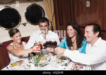 Two mid adult couples toasting with wine glasses and smiling Stock Photo