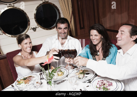 Two mid adult couples toasting with wine glasses and smiling Stock Photo