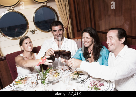 Two mid adult couples toasting with wine glasses and smiling Stock Photo