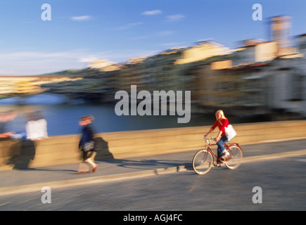 Female biking on Ponte St Trinita over Arno River in Florence Stock Photo