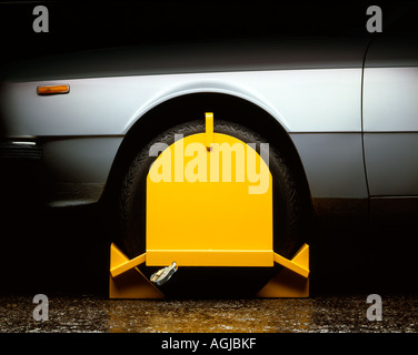 Yellow Wheel Clamp on a silver car Stock Photo