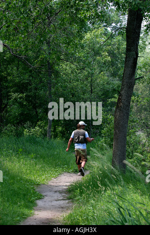 River Little Manistee MI USA young fisherman Caucasian man wearing a fishing vest from front walks in the forest path hi-res Stock Photo