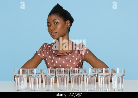 Young woman with eight glasses of water Stock Photo