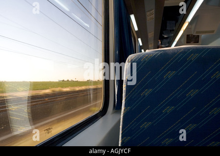 View from interior of moving train of passing countryside and of seat in front Spain Stock Photo