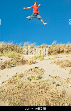 Young Man leaping from a Sand Dune Braunton Burrows Devon UK Stock Photo