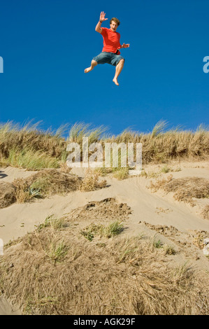Young Man leaping from a Sand Dune Braunton Burrows Devon UK Stock Photo