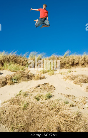Young Man leaping from a Sand Dune Braunton Burrows Devon UK Stock Photo