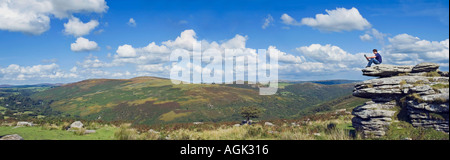 Young man sitting on a rock reading a magazine in open countryside Stock Photo