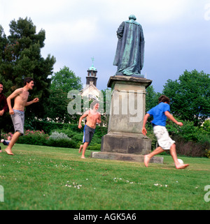 Cardiff University students playing football around statue in the park Wales UK  KATHY DEWITT Stock Photo