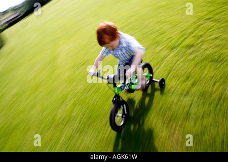 Boy cycling on a bike with stabilisers Stock Photo