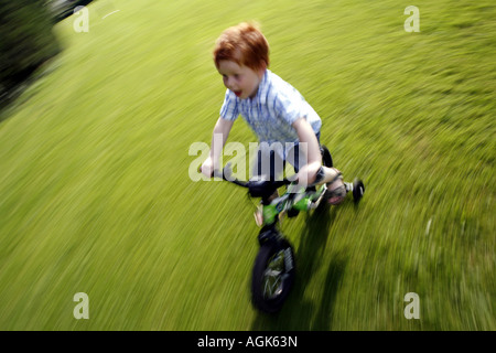 Boy cycling on a bike with stabilisers Stock Photo