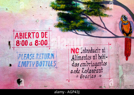 Mexico, Puerto Vallarta. Painting of parrot in tree next to sign text on wall. Stock Photo