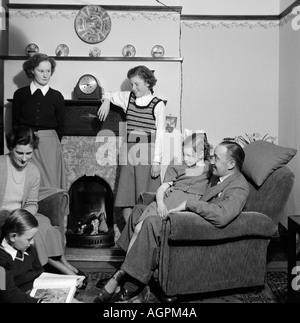 OLD VINTAGE FAMILY SNAPSHOT PHOTOGRAPH OF  MOTHER FATHER AND FOUR CHILDREN RELAXING IN LIVING ROOM OF HOUSE 1950 Stock Photo