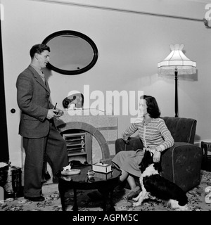 OLD VINTAGE BLACK AND WHITE FAMILY SNAPSHOT PHOTOGRAPH OF MARRIED COUPLE IN LIVING ROOM CIRCA 1950 Stock Photo