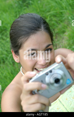 Portrait of a smiling young woman looking up using a digital camera Stock Photo