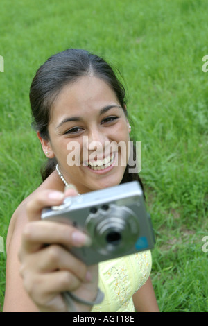Portrait of a smiling young woman looking up using a digital camera Stock Photo