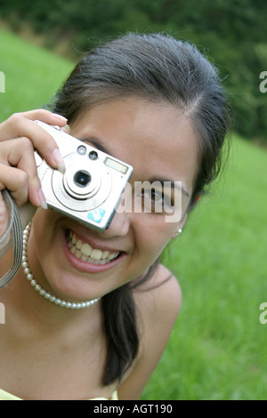 Portrait of a smiling young woman looking up using a digital camera Stock Photo