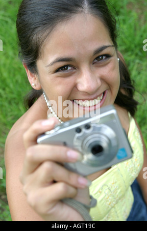 Portrait of a smiling young woman looking up using a digital camera Stock Photo