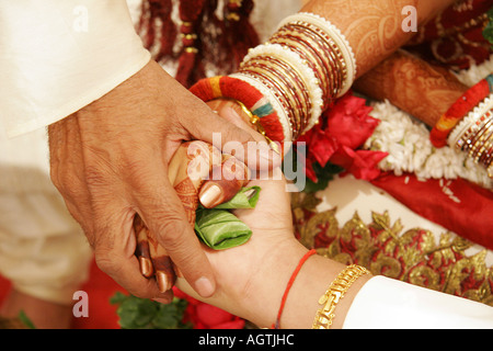 SSK79517 The ritual called Hastmelap being performed during Indian Gujarati wedding brides hand on bridegrooms hand Stock Photo