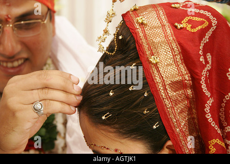 Indian Gujarati Bridegroom putting red powder called Sindoor on brides forehead as ritual of Indian Wedding and sign of marriage Stock Photo