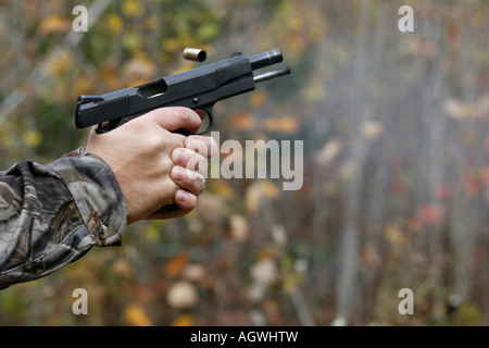 Semi-auto pistol being shot and the empty shell being ejected. Stock Photo