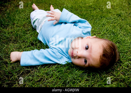 a baby enjoying sun light in the garden on the green grass Stock Photo