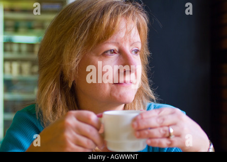 Attractive middle aged woman drinking coffee in a restaurant Stock Photo