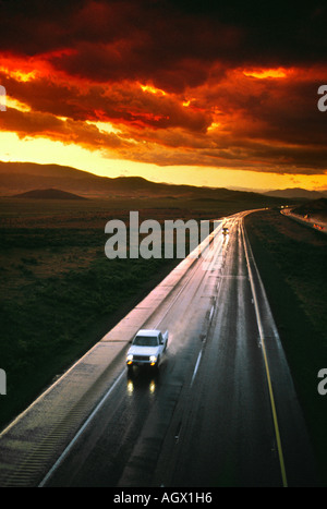High angle view of cars on freeway interstate highway as sun sets Storm clouds nearby Stock Photo