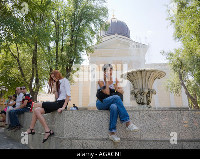 Two young women using their mobile phones in front of the Spaso Preobrazhenskiy Cathedral in Odessa / Ukraine Stock Photo