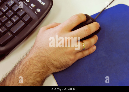 Male hand holding a computer mouse near a black keyboard Stock Photo