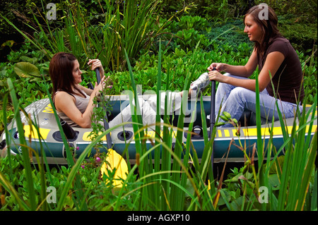 summertime.Two pretty girls in dingy alongside reeds.etc. Stock Photo