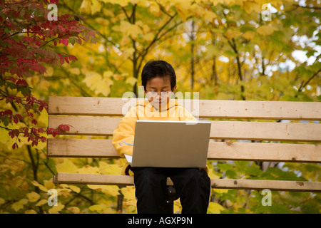 Asian boy doing homework on laptop in a park Stock Photo