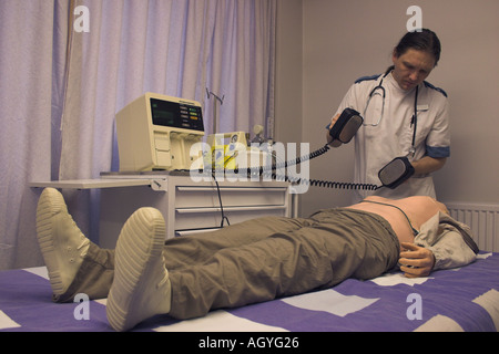 male nurse training life support resuscitation techniques with electric defibrillation pads and a doll Stock Photo