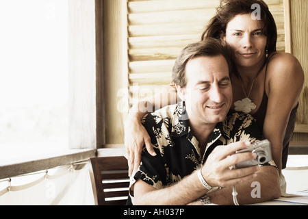 Close-up of a mid adult man holding a digital camera with a mid adult woman beside him Stock Photo