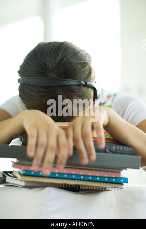 Teen girl resting head on stack of homework Stock Photo