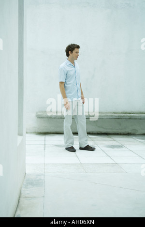 Man standing in courtyard, looking away, full length portrait Stock Photo