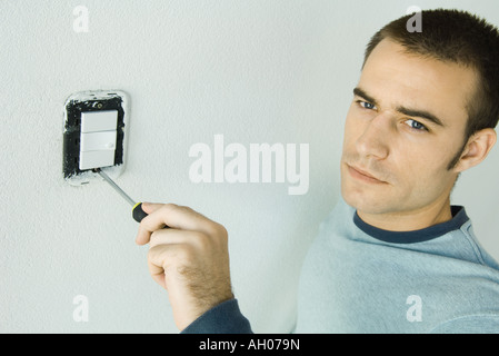 Man removing light switch cover Stock Photo