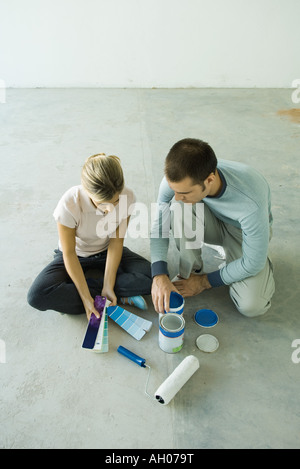 Couple sitting on floor looking at color swatches Stock Photo
