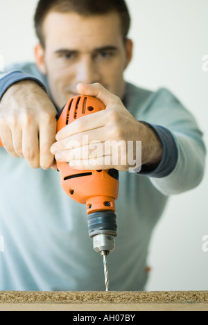 Man using drill, focus on drill in foreground Stock Photo