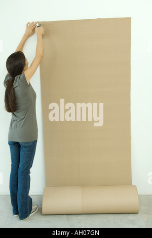 Woman stapling corrugated cardboard to wall Stock Photo