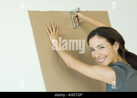 Woman stapling corrugated cardboard to wall Stock Photo