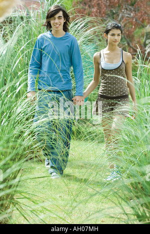 Young couple walking through long grasses of ornamental garden Stock Photo