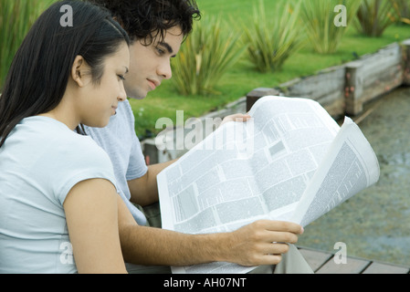 Young couple reading newspaper together outdoors Stock Photo