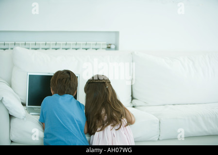 Boy and girl using laptop on sofa, rear view Stock Photo